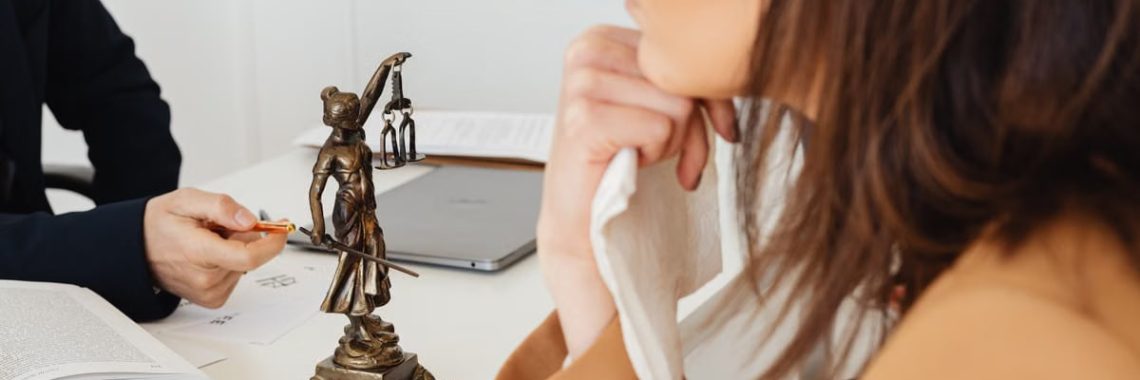 A professional setting with a Lady Justice statue, two individuals discussing legal matters.